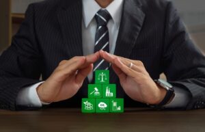 Businessman protecting green wooden block that have environment law icons. 