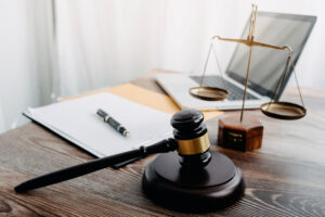 Lawyers and business professionals reviewing contract documents with brass scales of justice on desk, symbolizing legal services and advice.