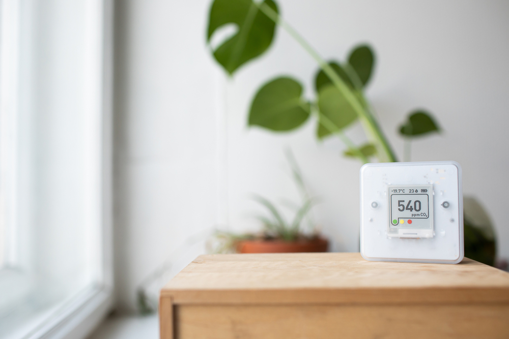 CO₂ sensor monitor measuring indoor air quality, showing carbon dioxide levels and airflow control for a healthy work environment or smart home.