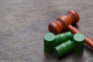 Wooden gavel beside toxic waste barrels, symbolizing environmental justice and legal action against pollution and hazardous waste violations.