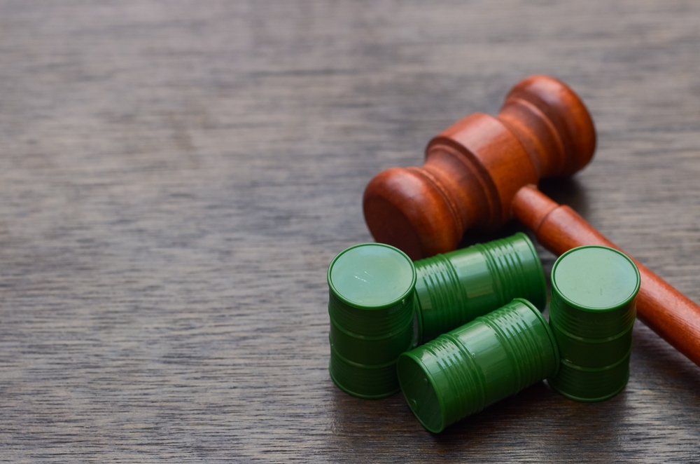 Wooden gavel beside toxic waste barrels, symbolizing environmental justice and legal action against pollution and hazardous waste violations.
